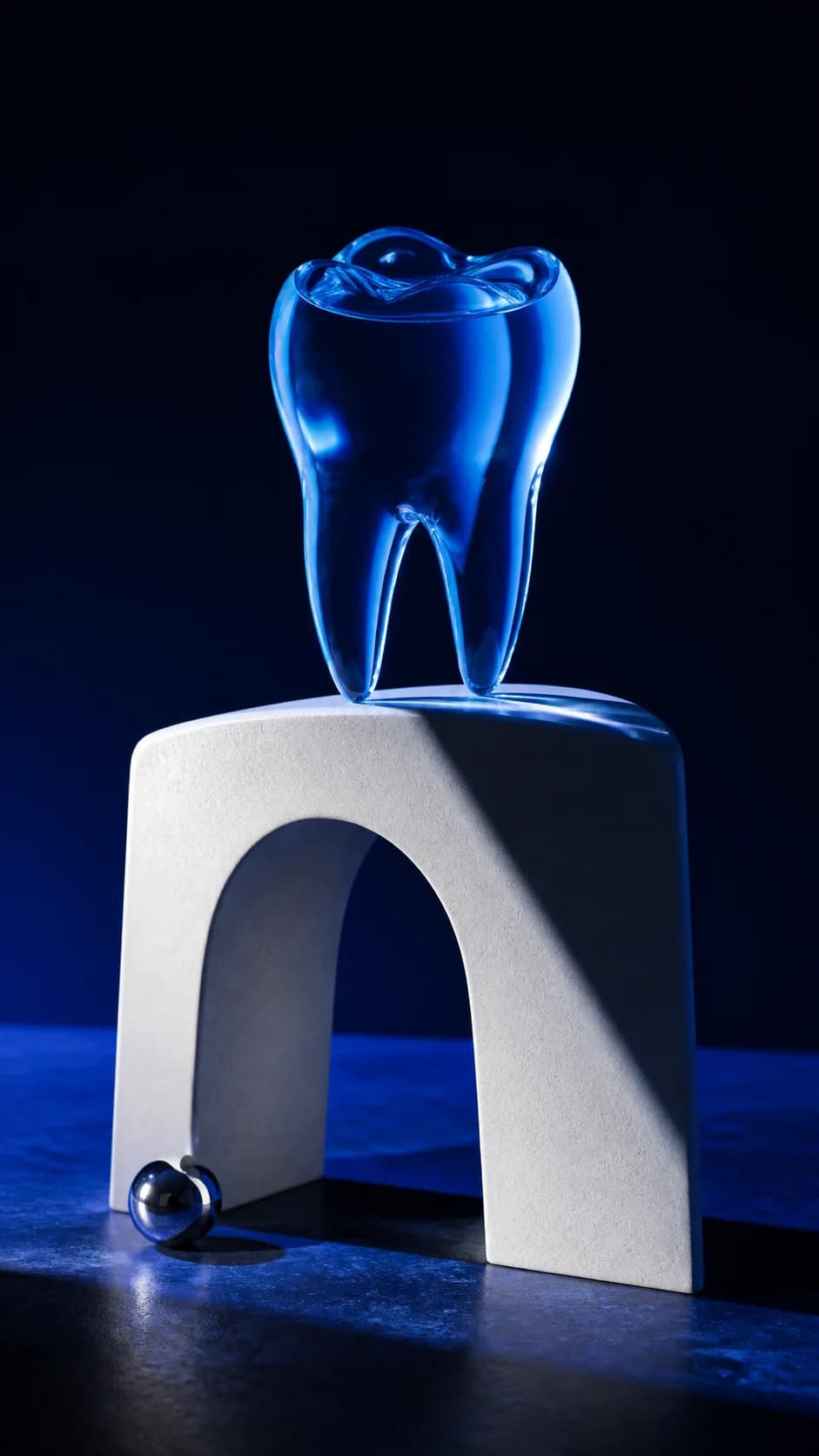 Concept still life of a translucent blue glass tooth and ceramic arch